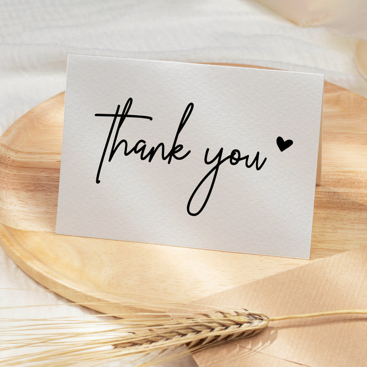 a thank you note sitting on top of a wooden plate