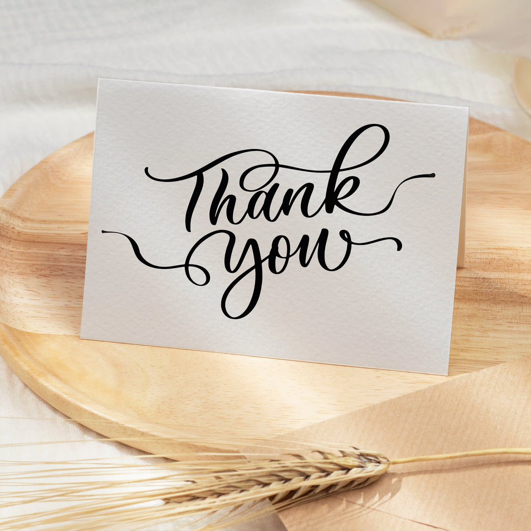 a thank you card sitting on top of a wooden plate