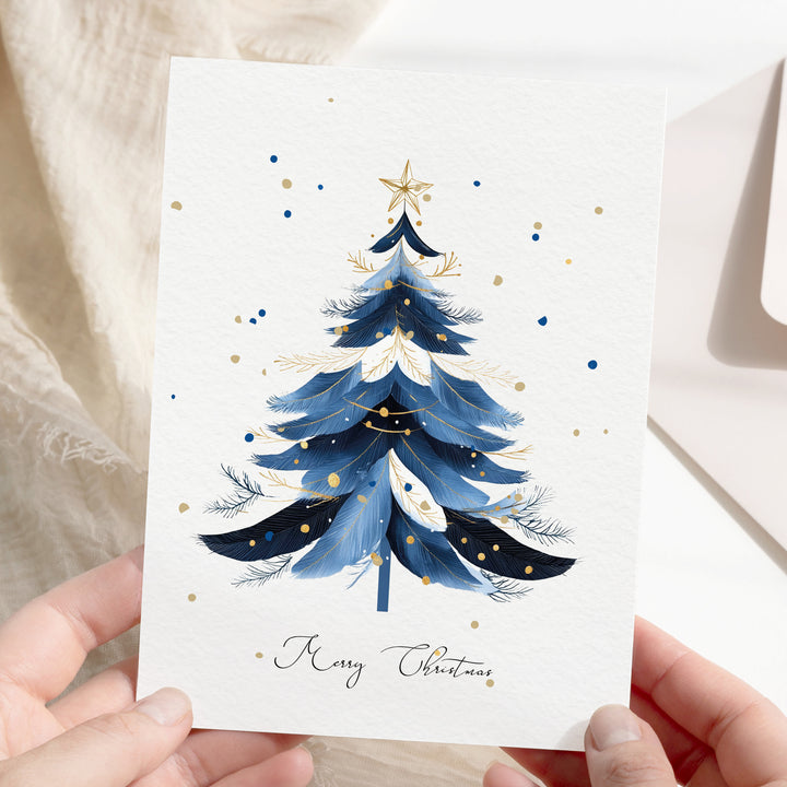 a person holding a card with a christmas tree on it