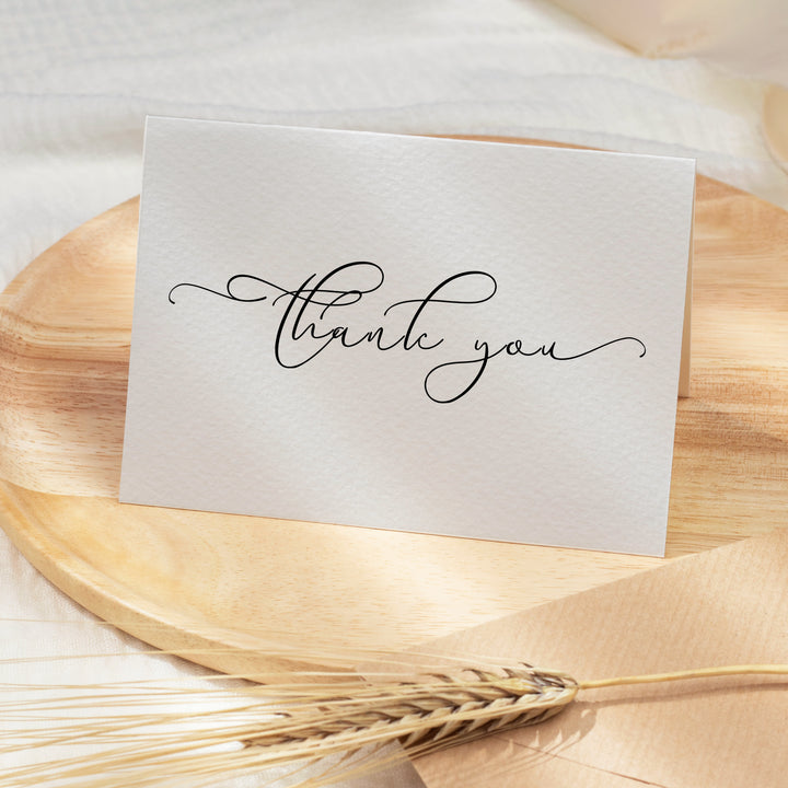 a thank you card sitting on top of a wooden plate