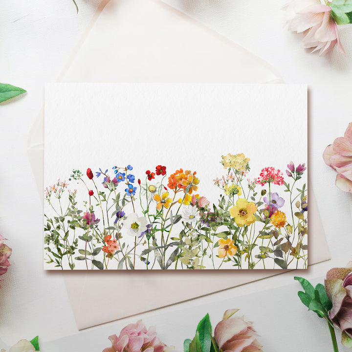 a card with a watercolor painting of a field of flowers