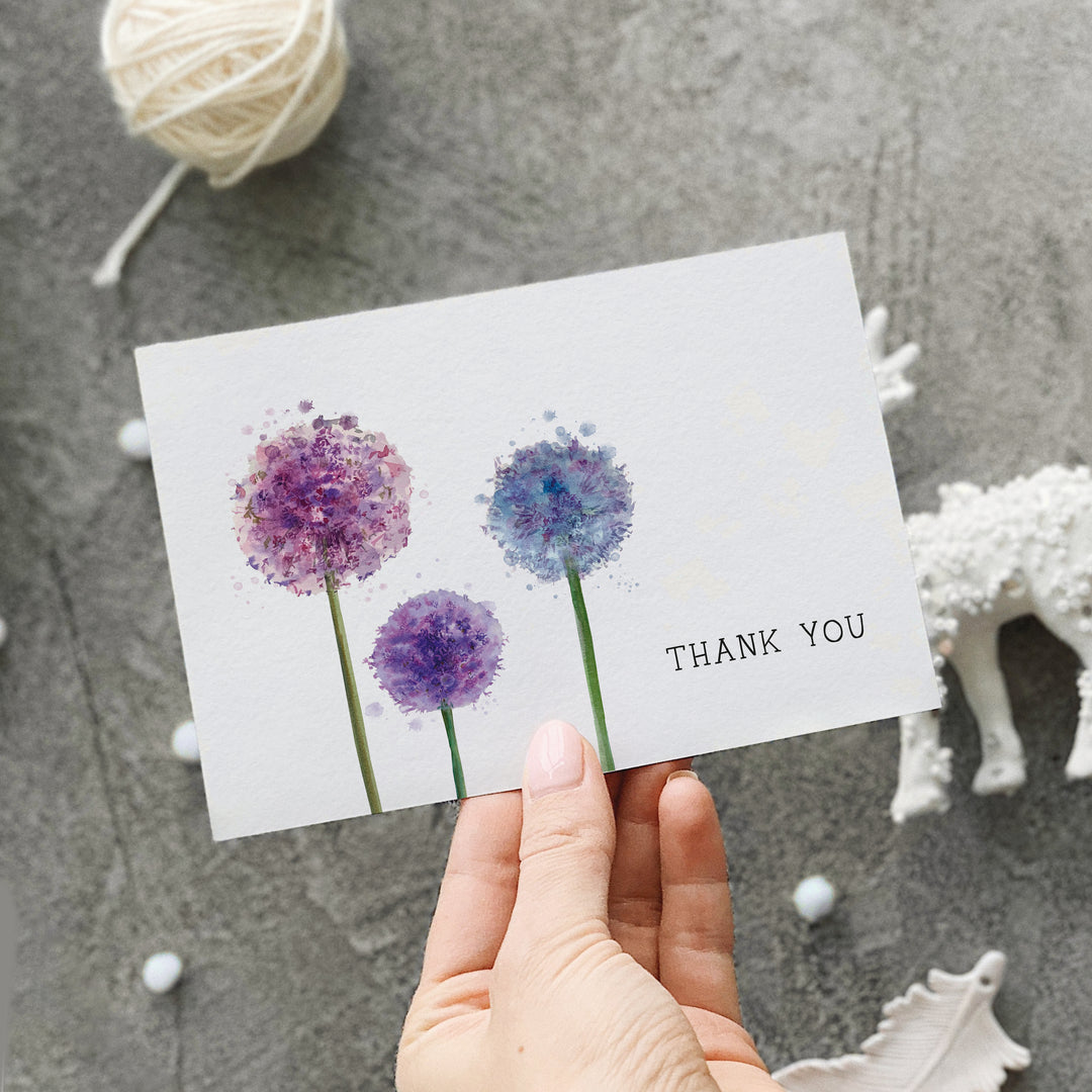 a hand holding a thank you card with three flowers