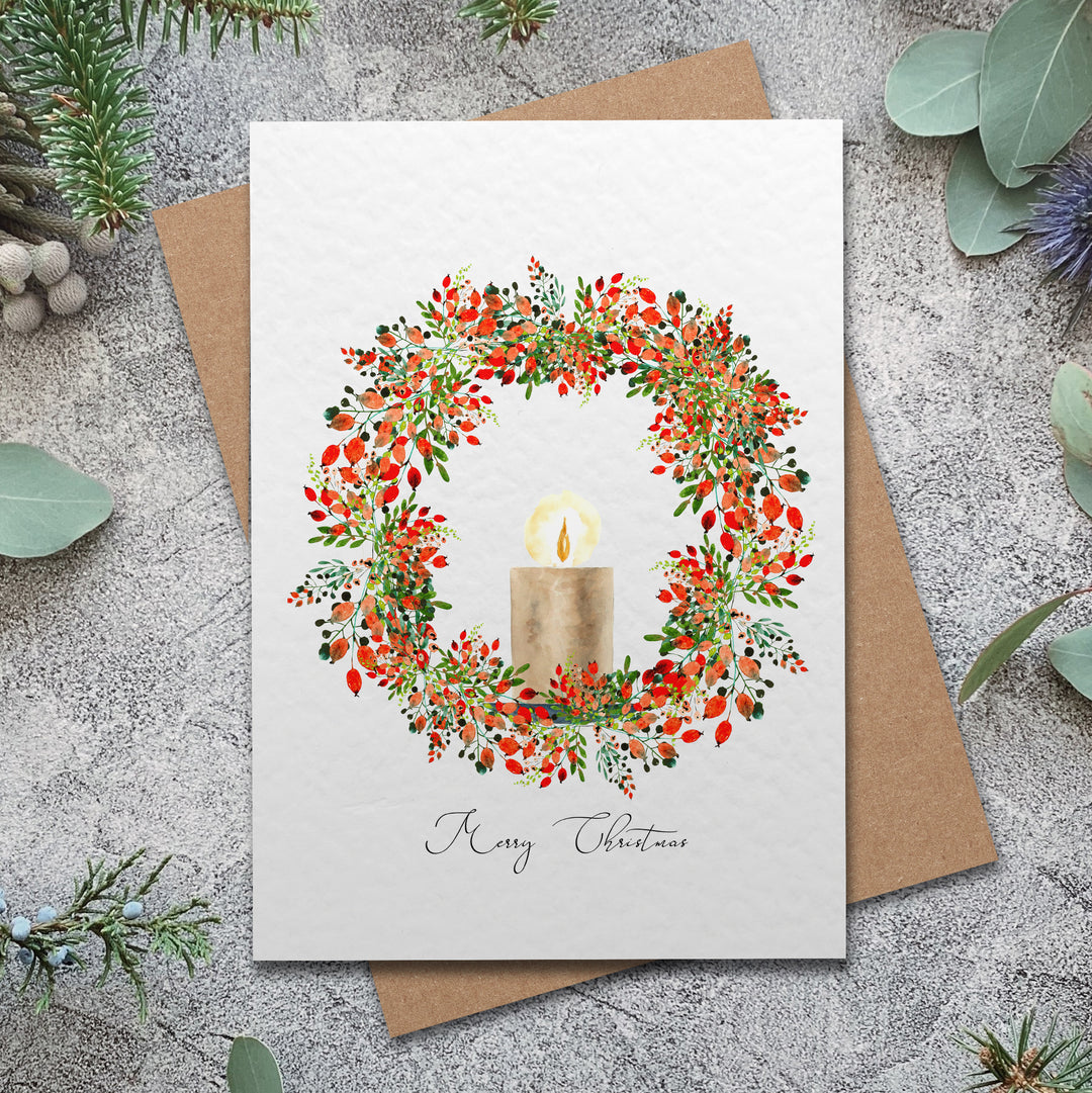 a christmas card with a candle surrounded by greenery