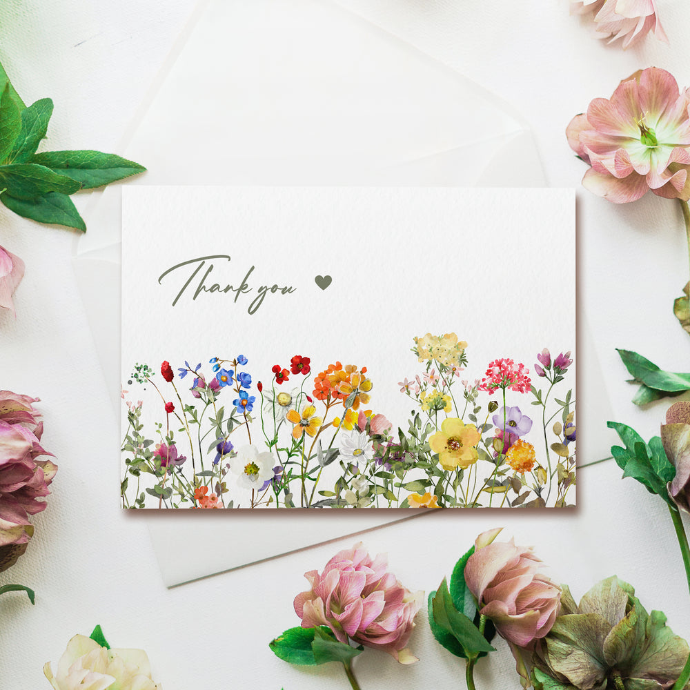 a thank you card surrounded by flowers and greenery