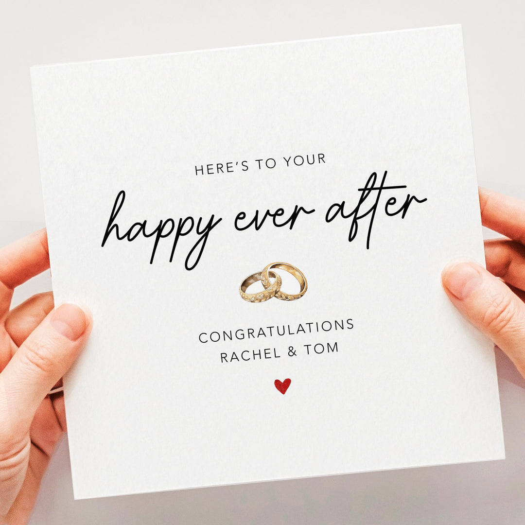 simple and elegant heres to your happy ever after card with handwritten font two intertwining gold wedding rings and a red heart
