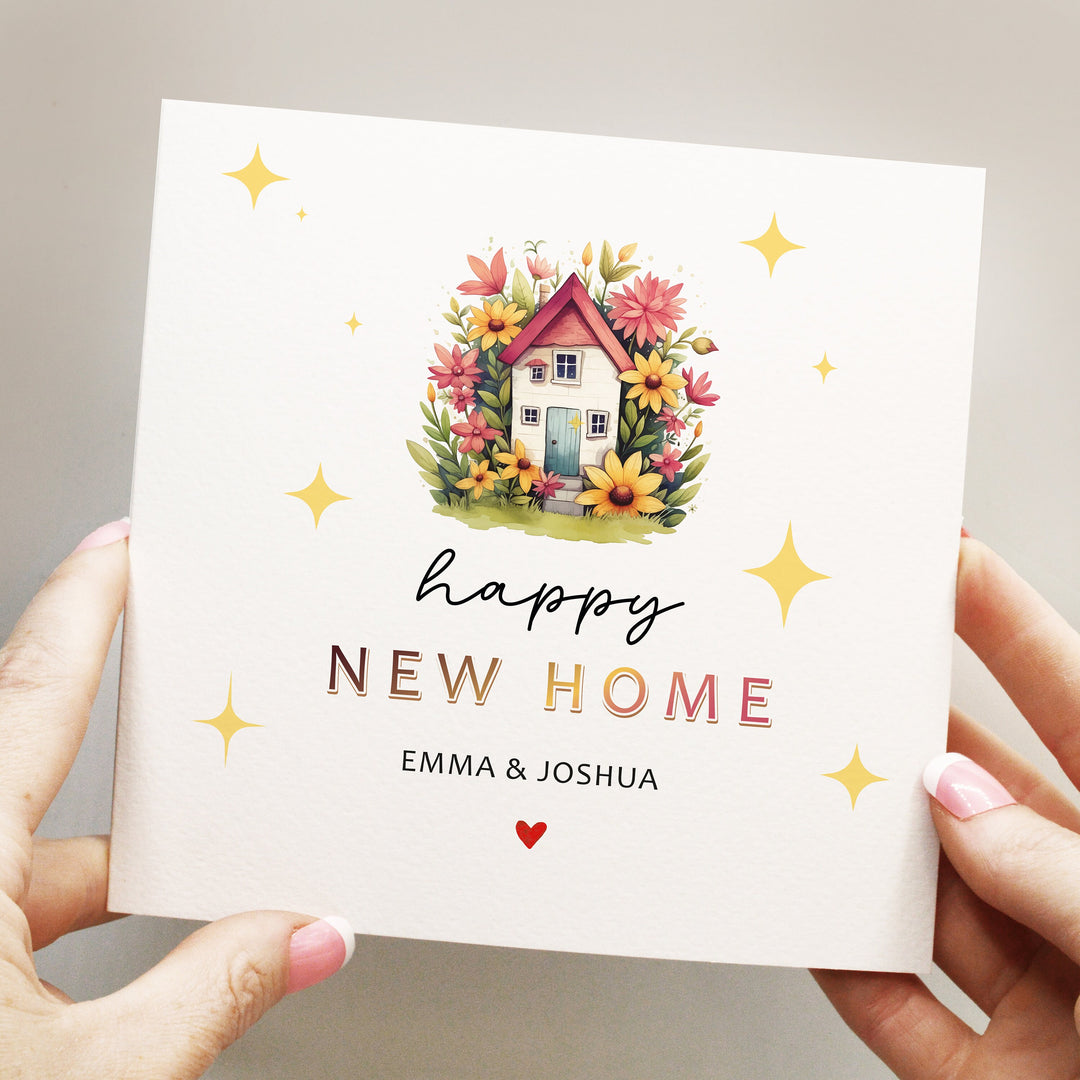 personalised happy new home card with cute and colourful house illustration surrounded by plants and flowers and yellow stars in the background with heart at the bottom