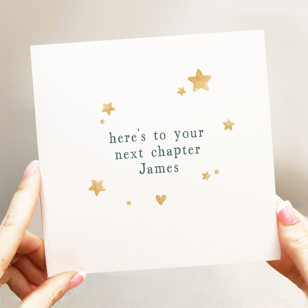 personalised heres to your next chapter card with neutral beige colour heart and stars and quirky serif font in dark blue